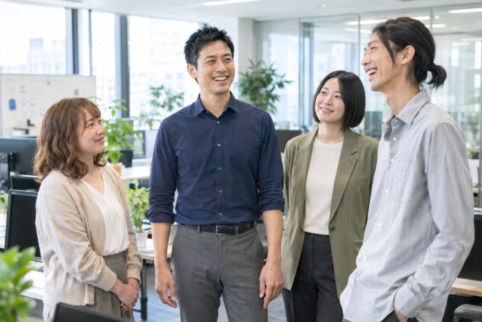 背すじが自然に伸びた姿勢で、笑顔で同僚と話す男性